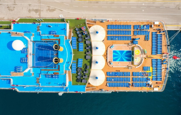 Vista aérea de pessoas da piscina em espreguiçadeiras guarda-chuvas no navio de cruzeiro no verão Vista de cima de pessoas relaxantes em espreguiçadeiras água azul no deck de madeira da piscina Resort de cruzeiro de luxo
