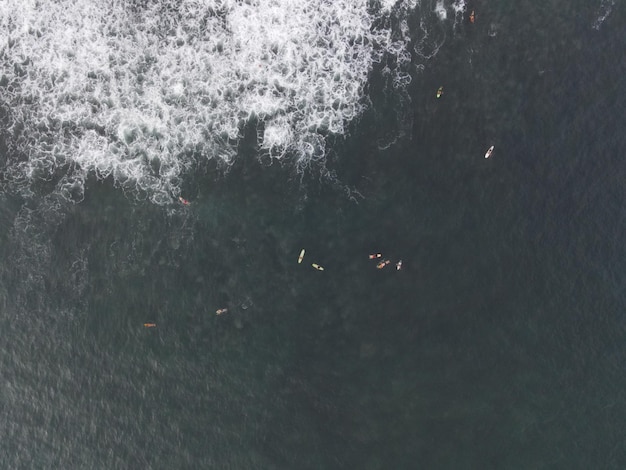 Vista aérea de pessoas surfando nas ondas com pranchas de surf durante as férias em Bali Indonésia