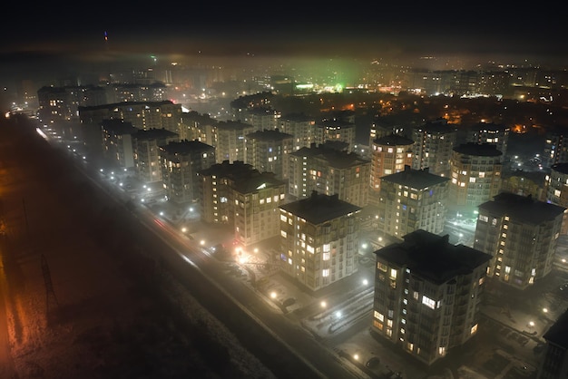 Vista aérea de prédios de apartamentos altos e ruas iluminadas brilhantes na área residencial da cidade à noite. Paisagem urbana escura