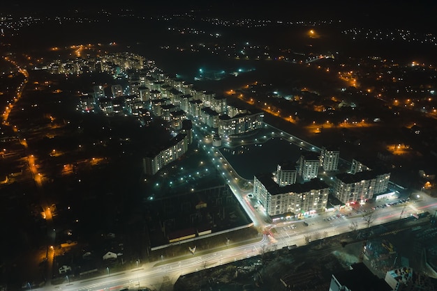 Vista aérea de prédios de apartamentos altos e ruas iluminadas brilhantes na área residencial da cidade à noite paisagem urbana escura