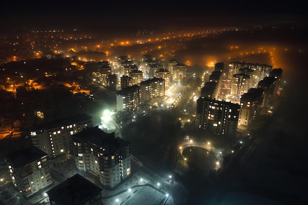 Vista aérea de prédios de apartamentos altos e ruas iluminadas brilhantes na área residencial da cidade à noite Paisagem urbana escura