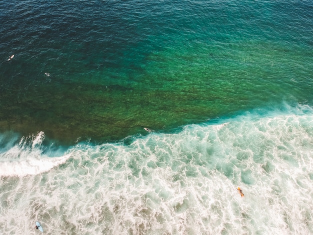 Vista aérea de surfistas nas ondas do Oceano Atlântico. Praia de areia