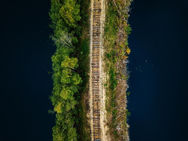 Vista aérea de trilhos de trem com floresta verde e lago azul na Finlândia rural