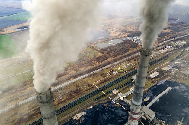 Vista aérea de tubos altos de usina de carvão com fumaça preta subindo a atmosfera poluente.
