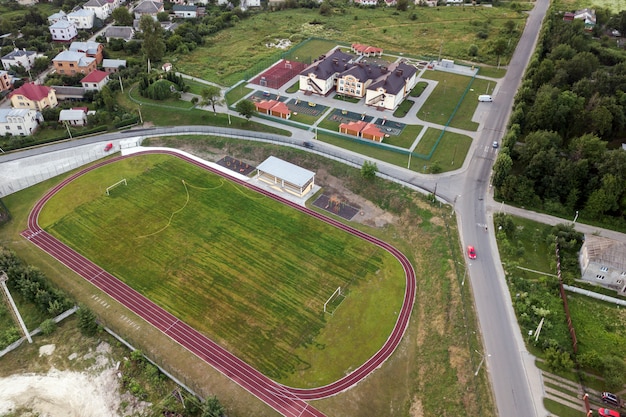 Vista aérea de um campo de futebol em um estádio coberto com grama verde na área da cidade rural.