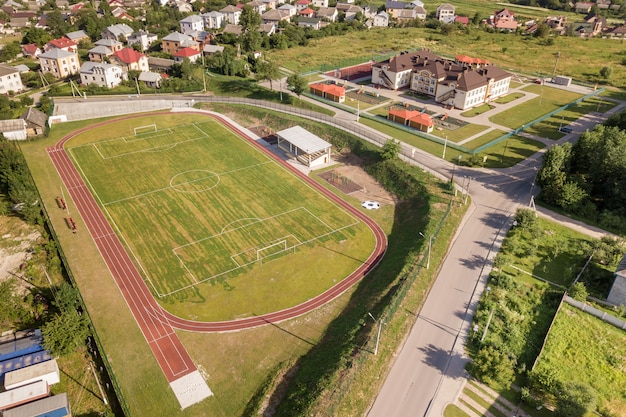 Vista aérea de um campo de futebol em um estádio coberto com grama verde na área da cidade rural.