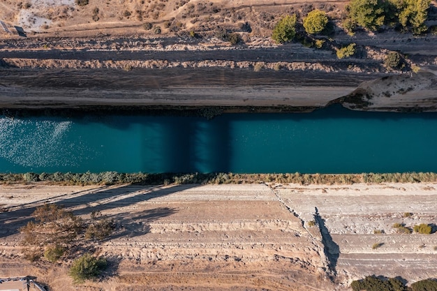 Vista aérea de um canal estreito e profundo de Corinto com água azul cortando a rocha Korinthos Grécia