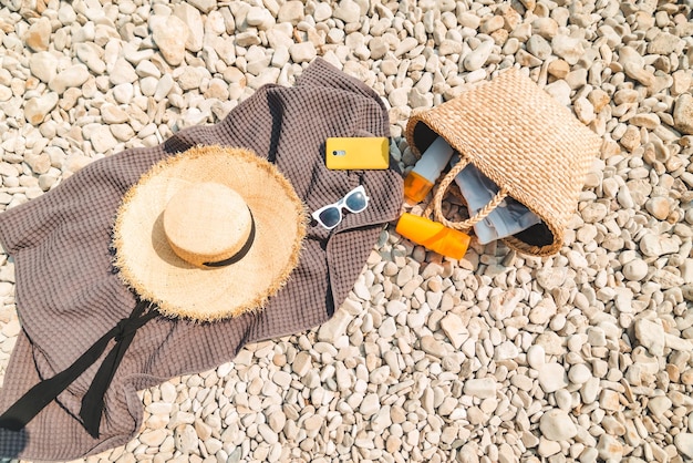 Vista aérea de um cobertor de praia com protetor solar e chapéu de palha creme com bolsa plana