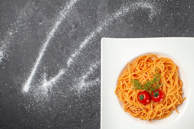 Vista aérea de um delicioso spagetty servido com tomates verdes em um prato quadrado sobre fundo preto e branco