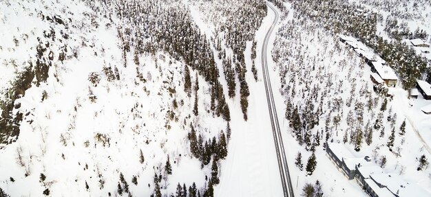 Vista aérea de um drone de uma estrada em uma paisagem idílica de inverno. Uma rua atravessando a natureza a partir de uma vista de pássaro.