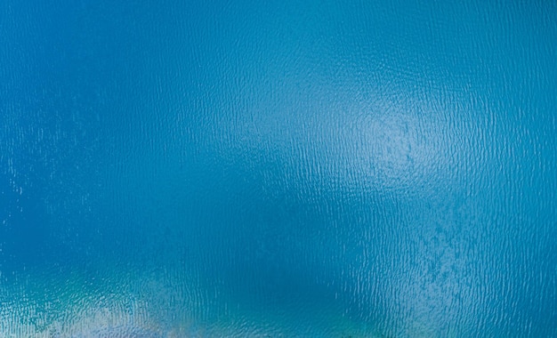 Vista aérea de um fundo de textura de água de superfície de mar azul e reflexões de sol vista aérea de drone voador textura de superfície de água de ondas no ensolarado oceano tropical na ilha de phuket, tailândia