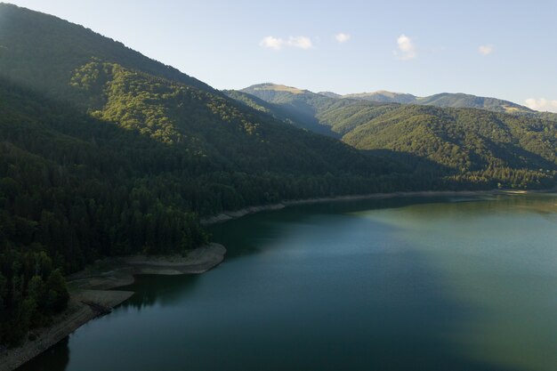 Vista aérea de um grande lago com águas azuis cristalinas entre colinas de alta montanha