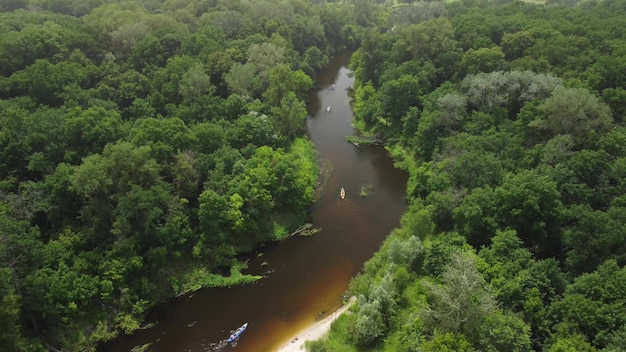 Vista aérea de um grupo de caiaques viajando em um rio da floresta em um dia de verão