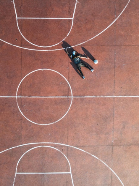 Vista aérea de um homem deitado no chão em uma quadra de basquete