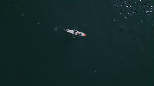 Vista aérea de um homem remando em uma prancha de stand up paddle ou SUP em um mar calmo