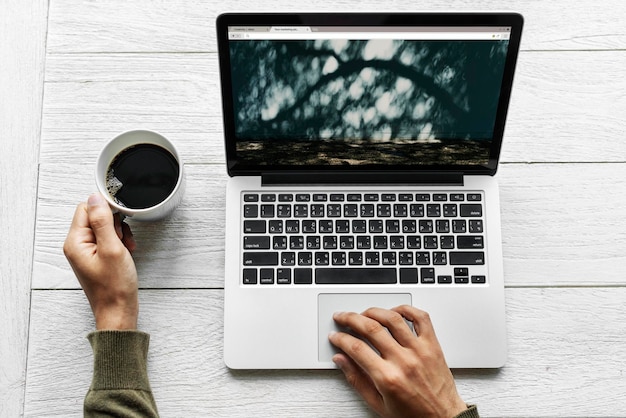 Vista aérea de um homem usando computador portátil na mesa de madeira