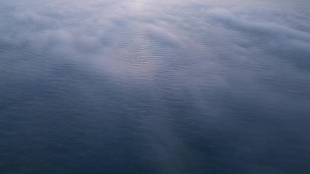 Vista aérea de um mar de nascer do sol com um cobertor de nevoeiro matinal e raios de sol matinais brilhando