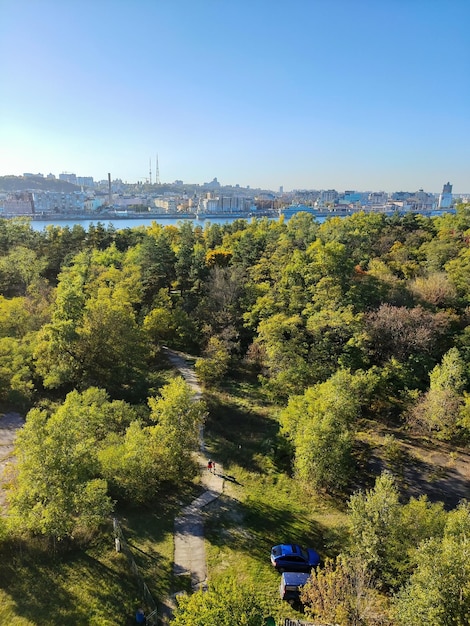 Vista aérea de um parque verde com muitas árvores e uma cidade ao longe com um rio