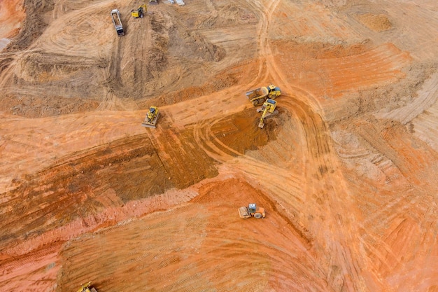 Vista aérea de uma escavadora industrial a carregar material de solo do local de construção de uma auto-estrada para uma