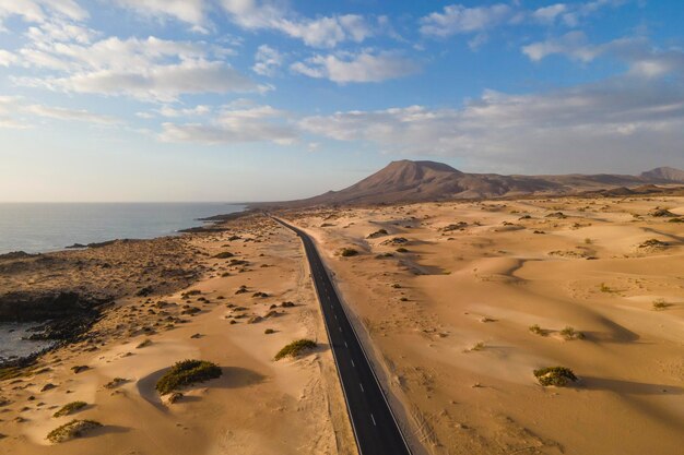 Foto vista aérea de uma estrada ao longo da costa que atravessa o parque natural das dunas de areia em corralejo fuerteventura, ilhas canárias, espanha