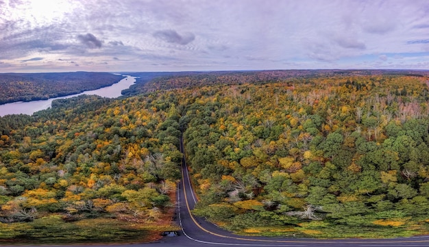 Vista aérea de uma estrada em meio a árvores contra um céu nublado durante o outono
