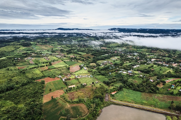 Vista aérea de uma fazenda de campo verde agrícola com névoa na zona rural em dia chuvoso