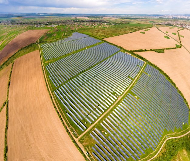 Vista aérea de uma grande usina elétrica sustentável com muitas fileiras de painéis solares fotovoltaicos para a produção de energia elétrica ecológica limpa. Eletricidade renovável com conceito de emissão zero.