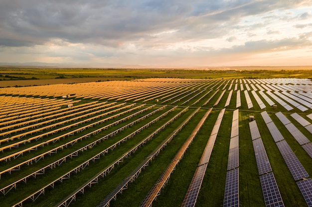 Vista aérea de uma grande usina elétrica sustentável com muitas fileiras de painéis solares fotovoltaicos para a produção de energia elétrica ecológica limpa. Eletricidade renovável com conceito de emissão zero.