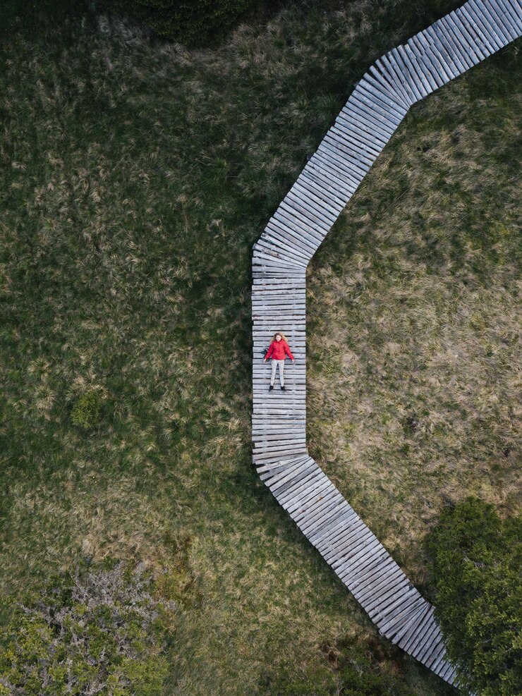 Foto vista aérea de uma mulher relaxando em uma calçada sobre um campo