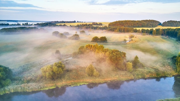 Foto vista aérea de uma paisagem rural com um rio e árvores exuberantes no nevoeiro