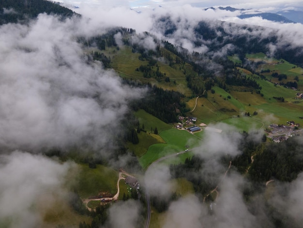 Vista aérea de uma pequena aldeia nas Dolomitas do sul do Tirol. Voando sobre as nuvens no italiano