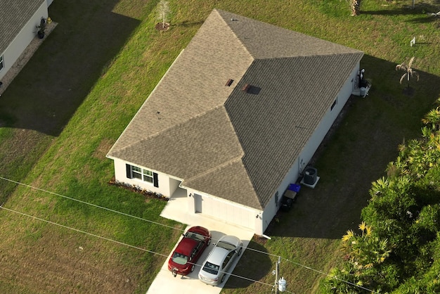 Vista aérea de uma típica casa privada americana contemporânea com telhado coberto de telhas de asfalto e gramado verde no quintal