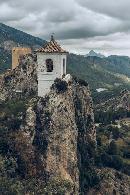 Vista aérea de uma torre sineira religiosa empoleirada em rochas em uma paisagem montanhosa