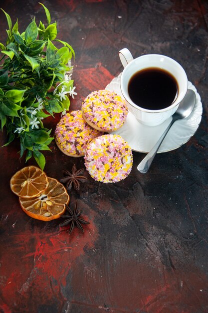 Vista aérea de deliciosas galletas de azúcar y una taza de maceta de café con rodajas de limón secas sobre fondo oscuro de colores mezcla