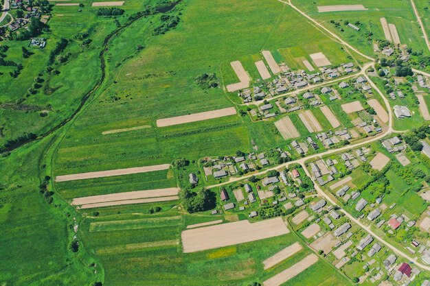 Vista aérea do alto da aldeia com casas e ruas, campos arados, prados no verão.