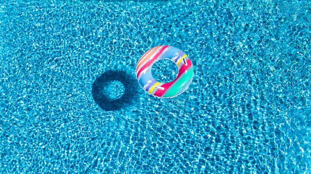 Vista aérea do brinquedo de donut de anel inflável colorido na água da piscina de cima, fundo do conceito de férias em família