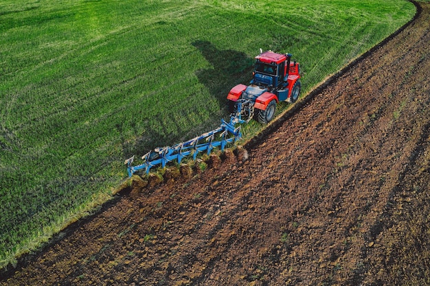 Vista aérea do campo de aração do trator na primavera