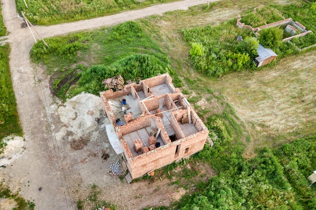 Vista aérea do canteiro de obras para futura casa, piso de porão de tijolo e pilhas de tijolos para construção.