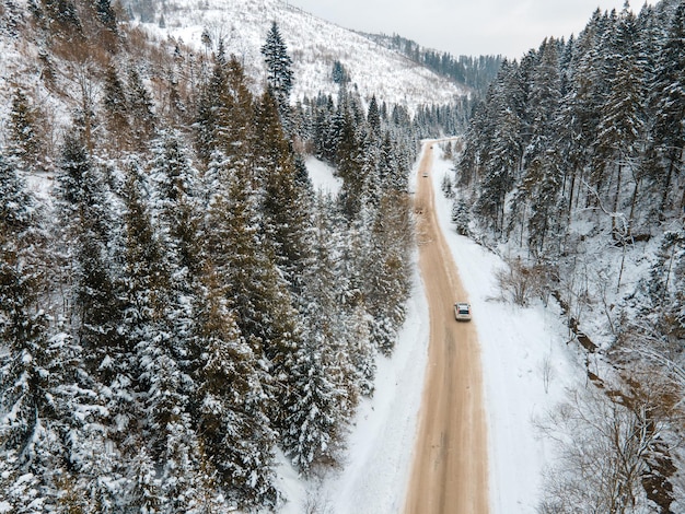 Vista aérea do carro na estrada nevada nas montanhas, temporada de inverno