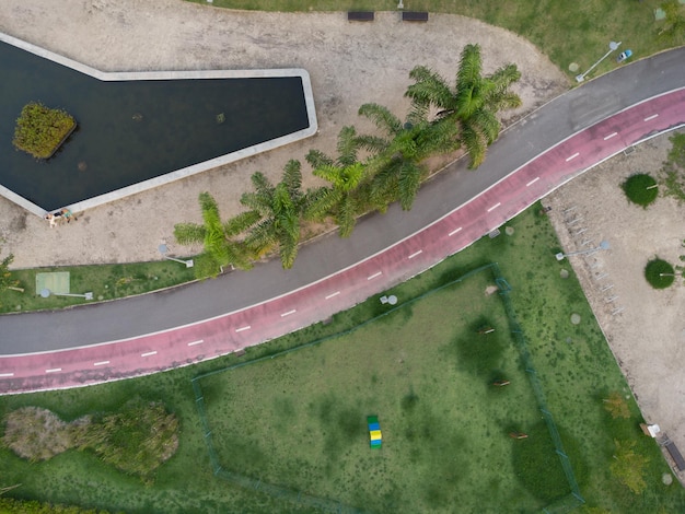 Vista aérea do Dog Place no Parque Ilha Pura ao pôr do sol. Coqueiros, espelho d'água e pista de corrida ao lado. Rio de Janeiro, Brasil. Dia ensolarado. Vista do topo. Drone leva.