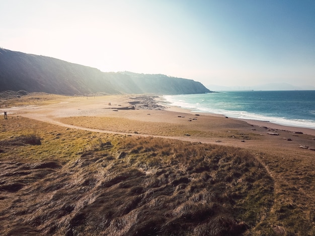 Vista aérea do drone das falésias com muitas ondas em uma praia rochosa e arenosa