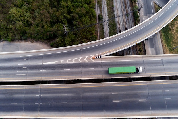 Vista aérea do drone de carga branca caminhão na estrada da rodovia com contêiner verde, conceito de transporte, importação, exportação logística industrial transporte transporte terrestre na via expressa de asfalto