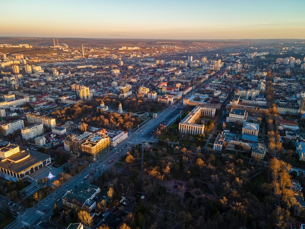 Vista aérea do drone de Chisinau ao pôr do sol. Vista panorâmica de vários edifícios, estradas com carros em movimento, árvores nuas, parques centrais. Moldova