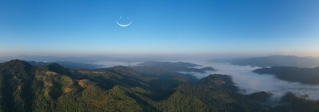 Vista aérea do drone paisagem panorâmica manhã céu azul claro natural e o processo de sorriso da lua e cordilheira com nevoeiro no vale em chiang rai Tailândia