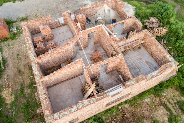 Vista aérea do estaleiro para futura casa, piso do porão de tijolo e pilhas de tijolos para construção.