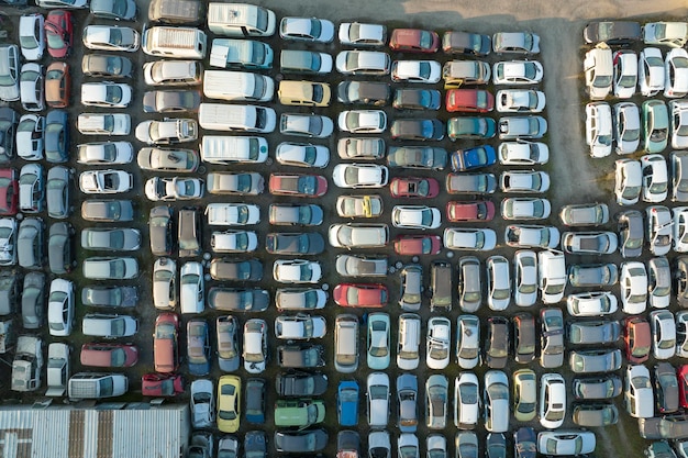 Vista aérea do grande estacionamento do ferro-velho com filas de carros quebrados descartados reciclagem de veículos antigos