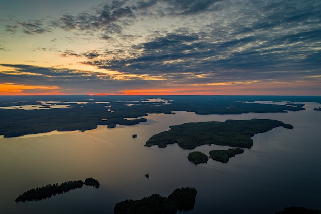 Vista aérea do lago Suoyarvi ao pôr do sol, cercado por florestas da Carélia, na Rússia