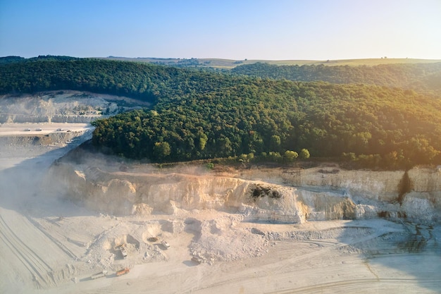 Vista aérea do local de mineração a céu aberto de extração de materiais calcários para a indústria da construção com escavadeiras e caminhões basculantes