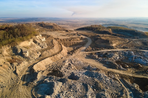 Vista aérea do local de mineração a céu aberto de materiais calcários para a indústria da construção com escavadeiras e caminhões basculantes