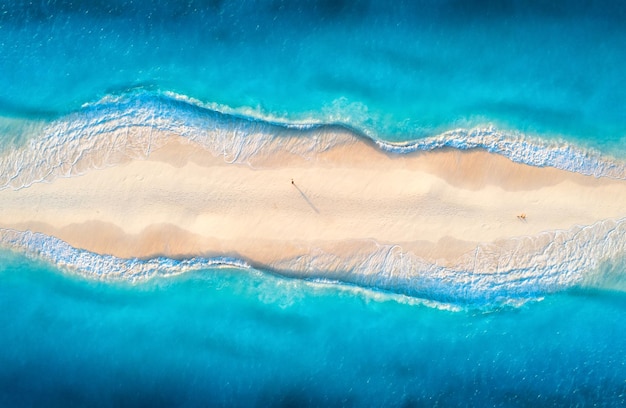 Vista aérea do mar azul transparente com ondas em ambos os lados e pessoas na praia ao pôr do sol Viagens de verão em Zanzibar África Paisagem tropical com areia branca da lagoa e vista superior do oceano